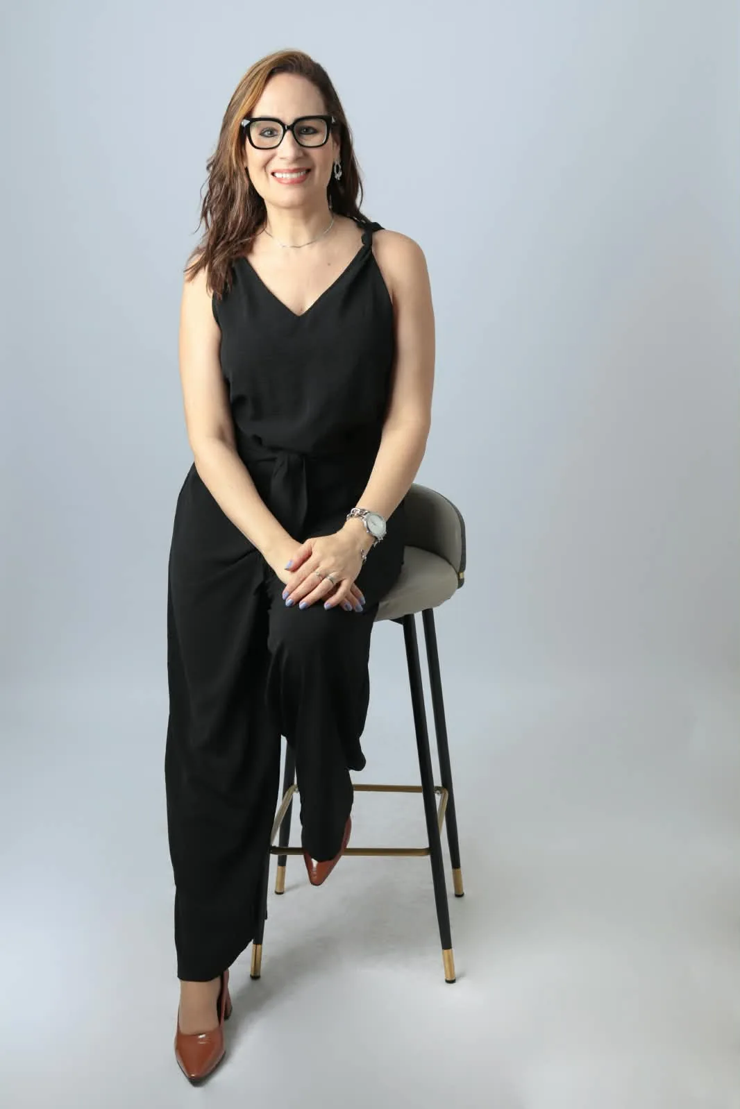 Dra. Fernanda Siqueira em retrato profissional sentada, usando óculos